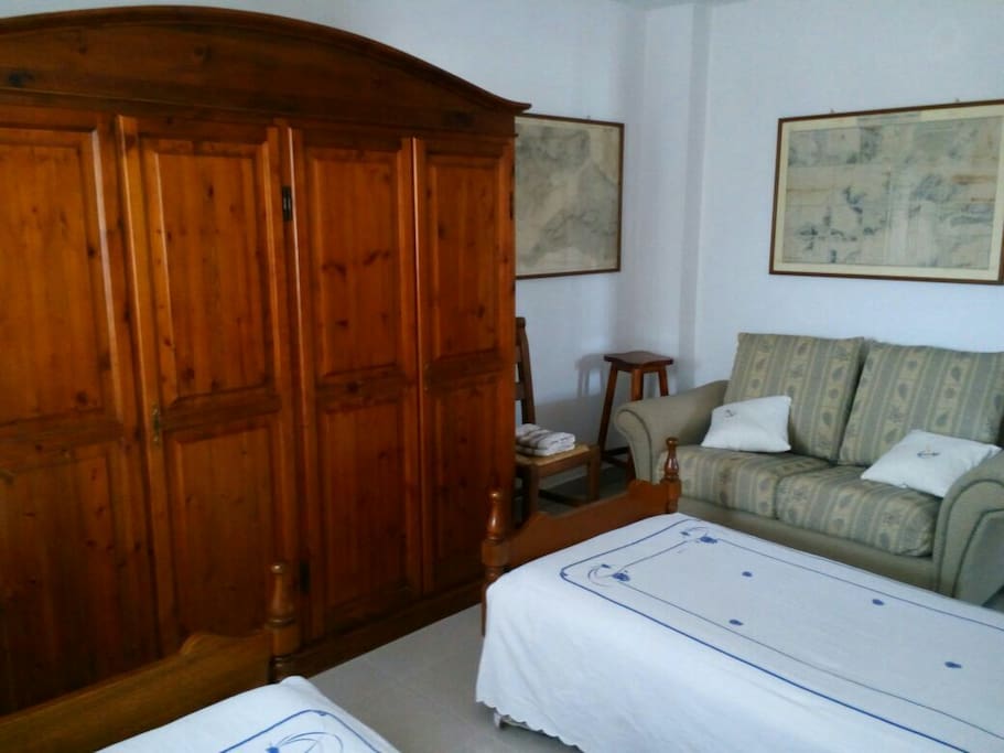 Small double bedroom with 2 single beds, wardrobe and couch.
