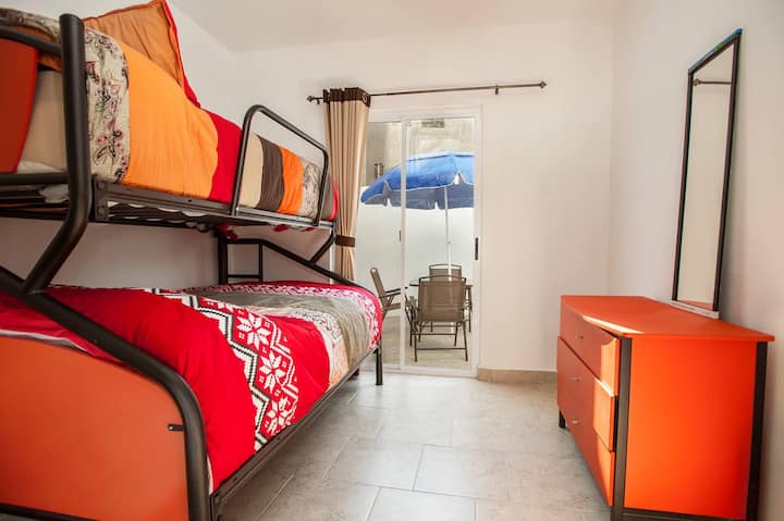 חדר שינה בקומת הקרקע עם מיטה זוגית ומיטת קומתיים אחת; עם גישה ישירה לחצר האחורית.