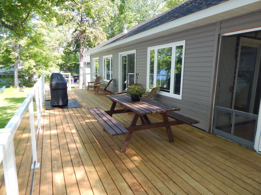 Deck with a picnic table, patio chairs, and glass paneled railings for an unobstructed view of the lake