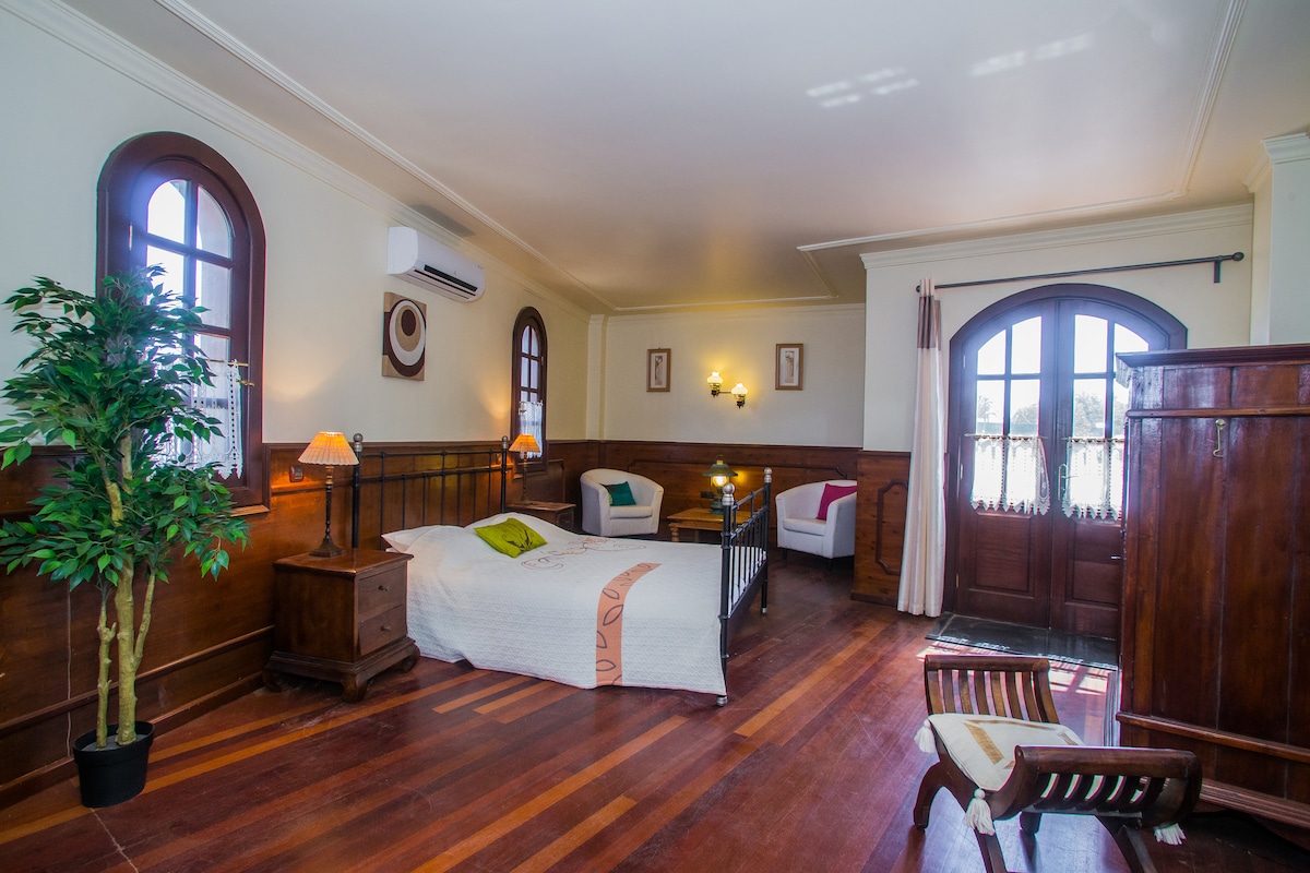 Голяма родителска спалня. Включено е огледало за суета, голям гардероб и масичка за кафе и столове. Вратите се отварят към тераса с изглед към басейна, морето и планината. 