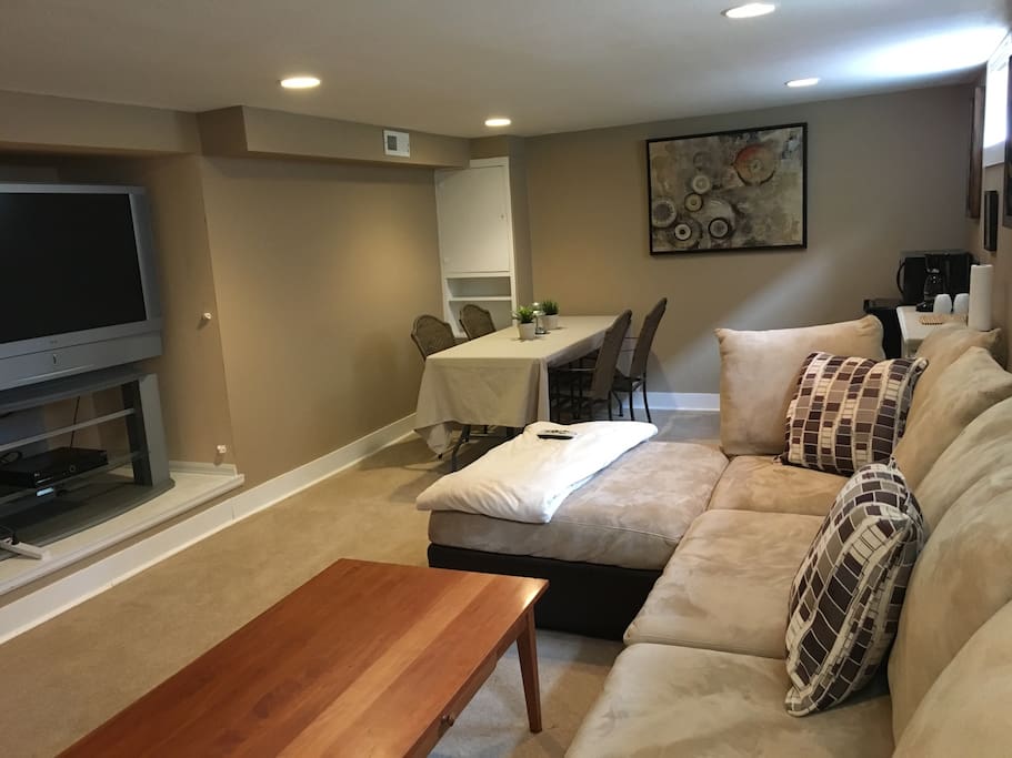 Large living area with tv, kitchenette, large sectional and seating for four people.