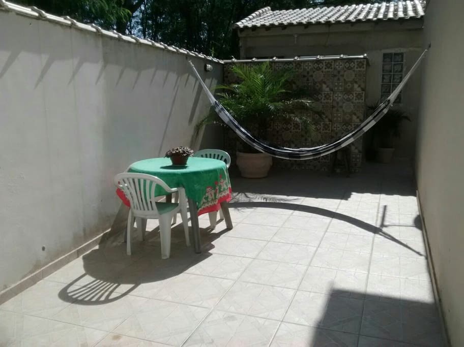 Quintal com rede, mesa e cadeira em área externa para café da manhã na área externa, jogos, bate papo.