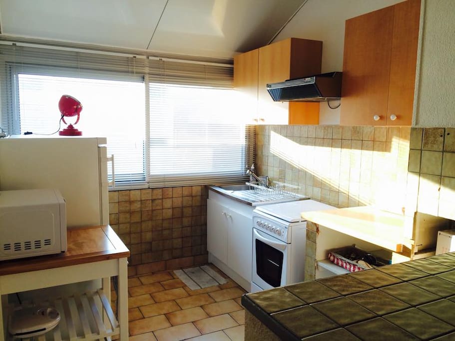 Fully equipped and well-lit kitchen with extractor fan + microwave + electric oven + toaster.