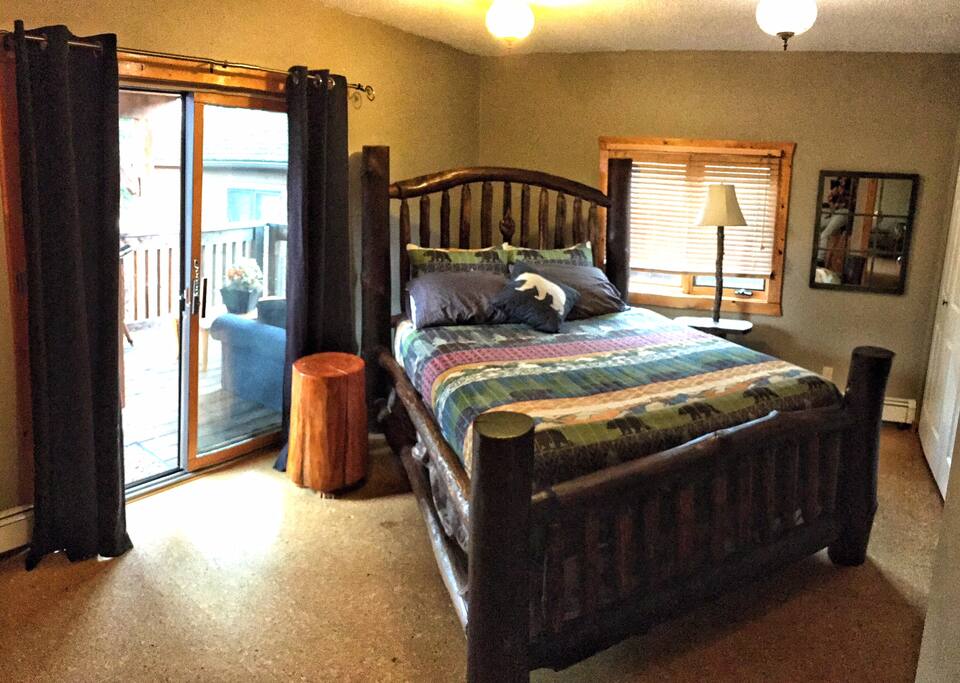 Spacious bedroom with custom log queen bed and patio door to private deck.