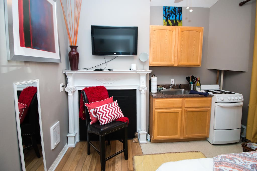 Kitchenette/ television 32”/stove/ cabinets (coffee maker, coffee, dishes, wine glasses in cabinet) Electric stove, wall heater next to chair.