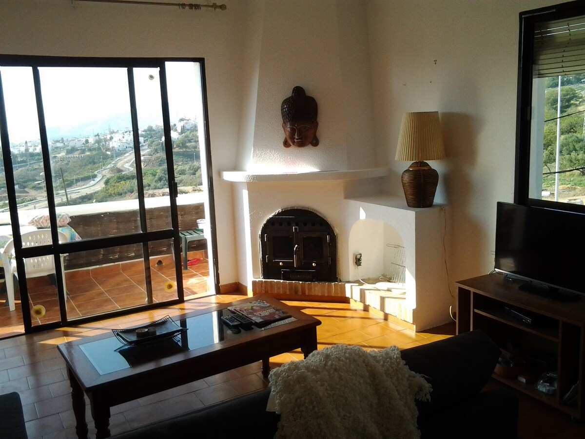 غرفة جلوس مع أريكة بسرير مزدوج وإطلالات على البحر والجبال ومدينة نيرجا. مكان لإشعال النار في الخشب.
