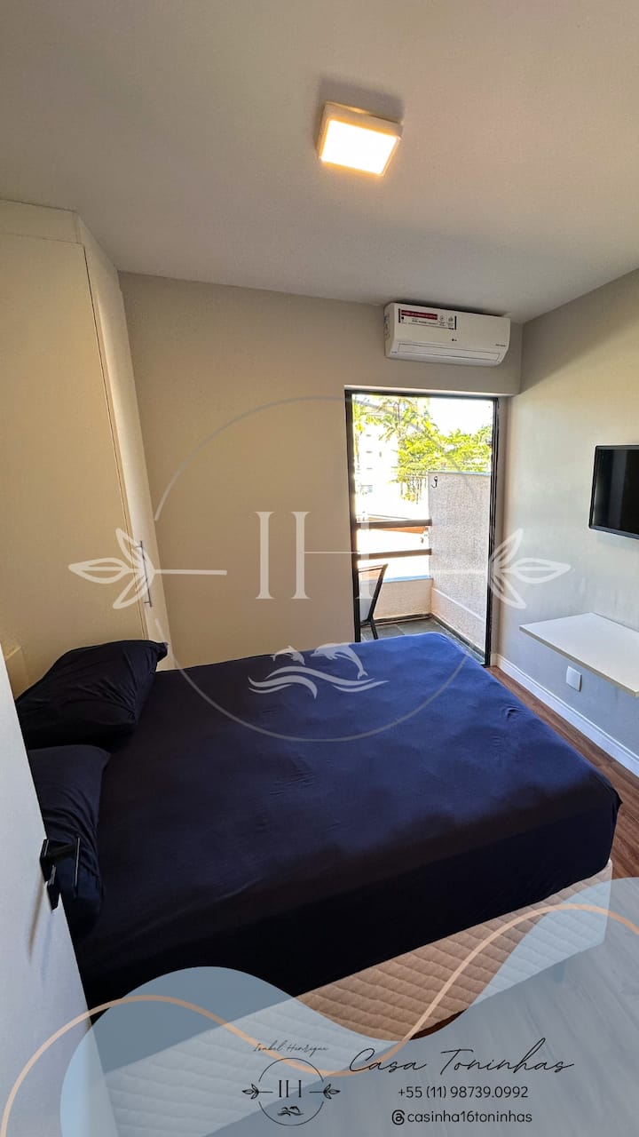 1张双人床（软床垫）、橱柜、桌子、空调和带椅子的阳台