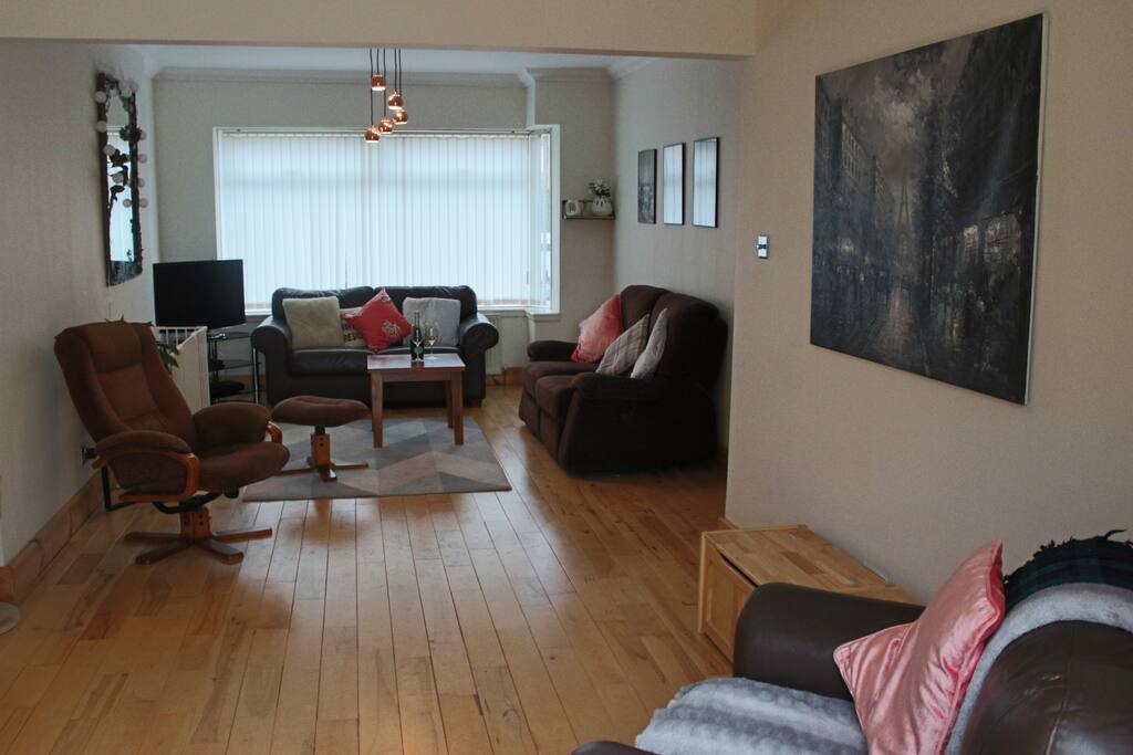 Living room with adjoining play space for children. Two boxes full of toys to play with. Arm chair on the left swivels to face either area.