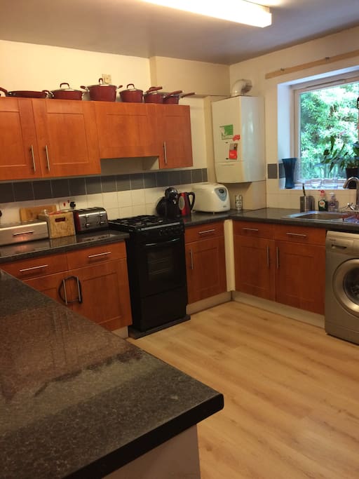 Kitchen with washing machine, cooker, microwave, food blender, coffee machine and bread machine.