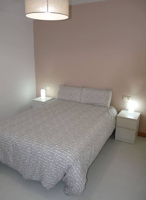 Vista dormitorio con cama doble, dos mesillas y dos lámparas individuales.