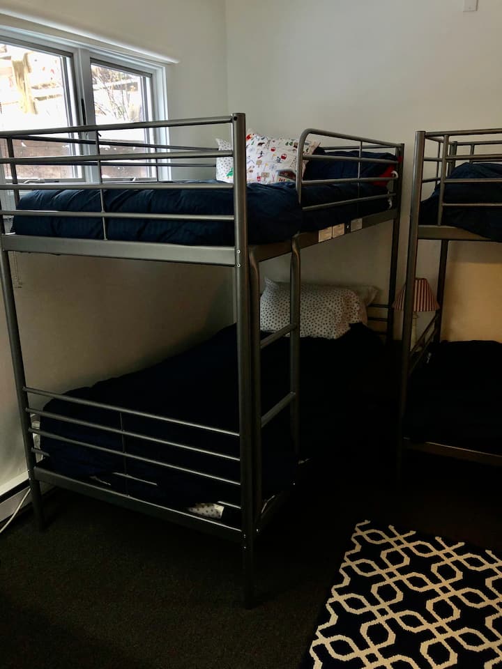 Habitación con literas en el primer piso con 2 ventanas. 2 juegos de camas individuales, vestidor, mesitas de noche y armario.