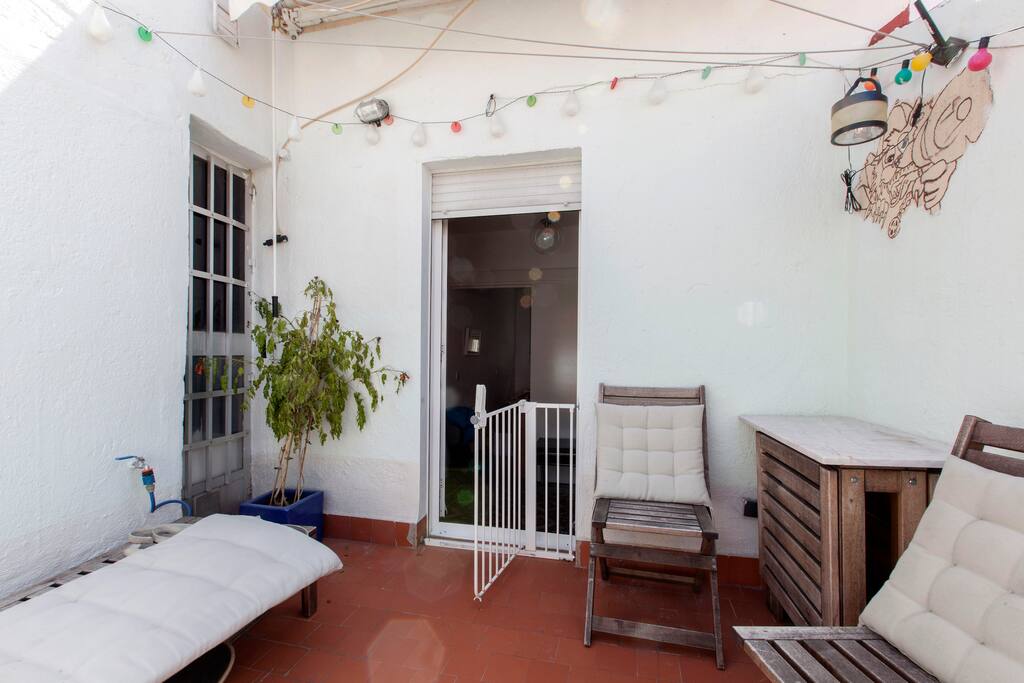 La terraza con mesa plegable, sillas, banco y tumbona.