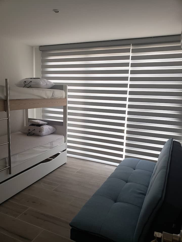 Habitación secundaria con una litera con 3 camas y un cómodo sofacama.