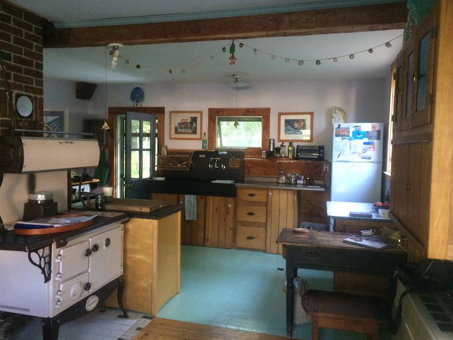 Sunny farm kitchen, slate sink, wood cook stove, live edge shelving... “normal” gas stove not visible around the wood one.