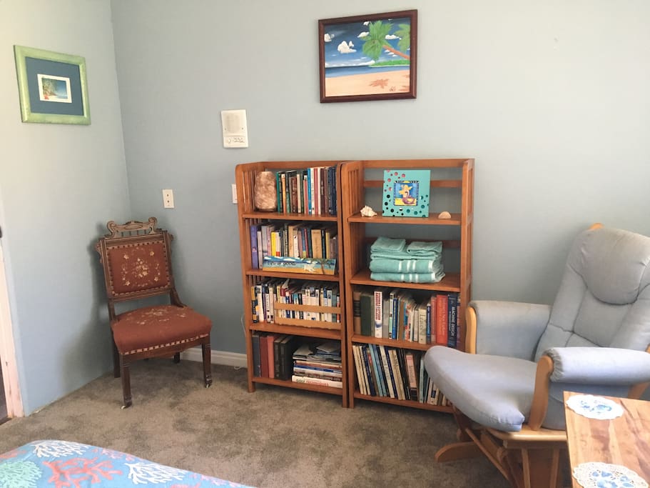 Beach themed decor, plenty of books to read and a comfy rocker to relax in.