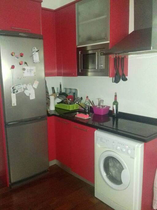 Cocina, con nevera, microondas, lavavajillas, vitrocerámica, cafetera, utensilios, suelo de madera,etc...