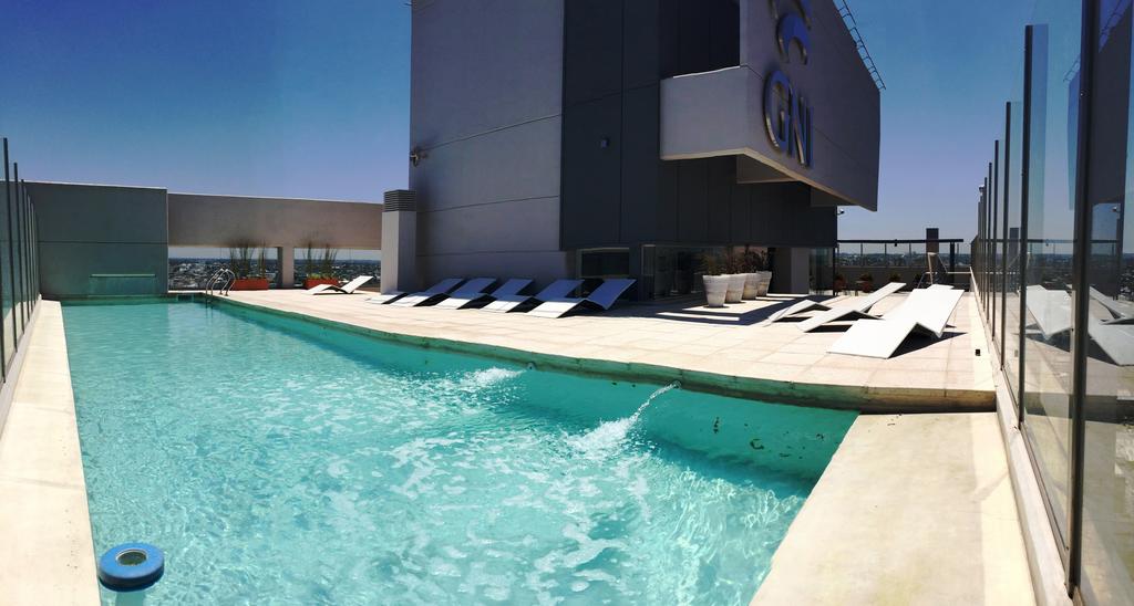 An outdoor pool area is highlighted by a clear turquoise pool with lounge chairs placed around its perimeter. The poolside features a spacious deck, enclosed by glass railing, showcasing panoramic views of the surrounding landscape.