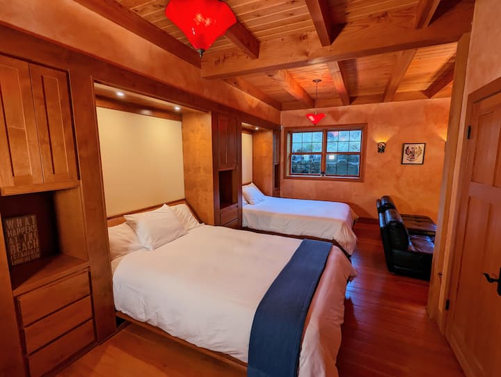 There are two deluxe wallbeds on the lower floor, along with a TV, couch, and full bathroom. The lower floor has high wood ceilings, heated wood floors, and looks out onto the private forest. 