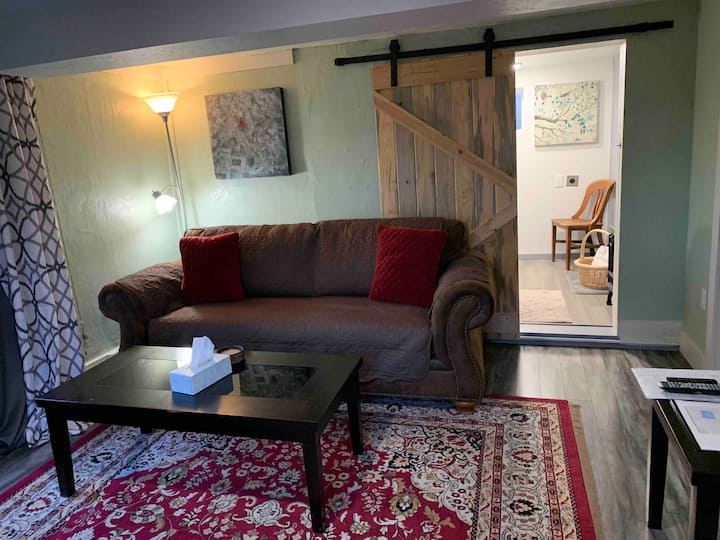 โซฟาปรับนอนขนาดควีนไซส์ (ห้องนั่งเล่น) พื้นหลังเป็นห้องซักรีด/ห้องอาบน้ำ 