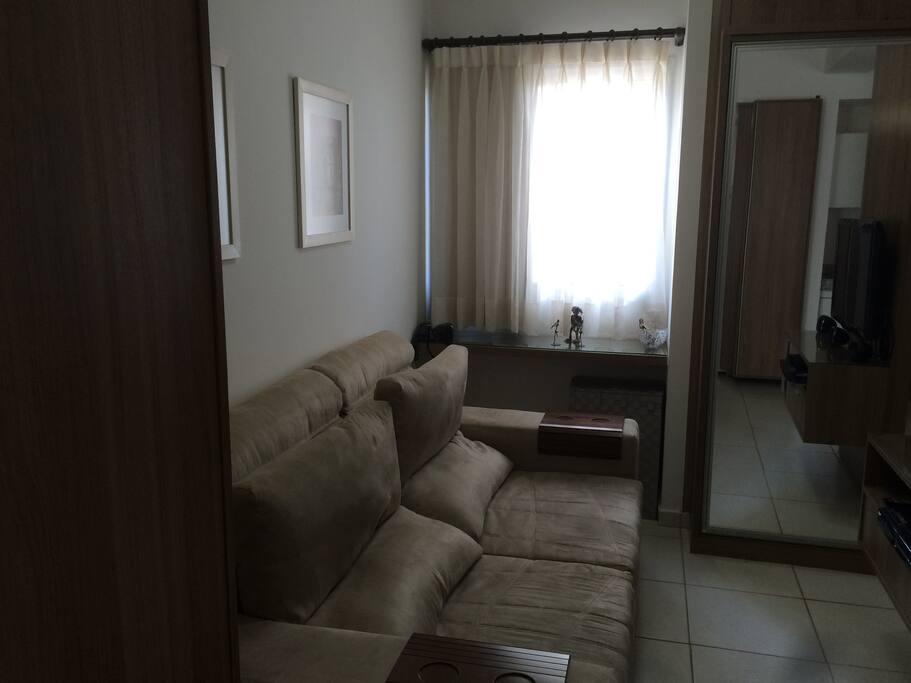 Mesmo sendo uma kit estúdio, a sala é ampla. Comporta 4 pessoas sentadas no sofá.