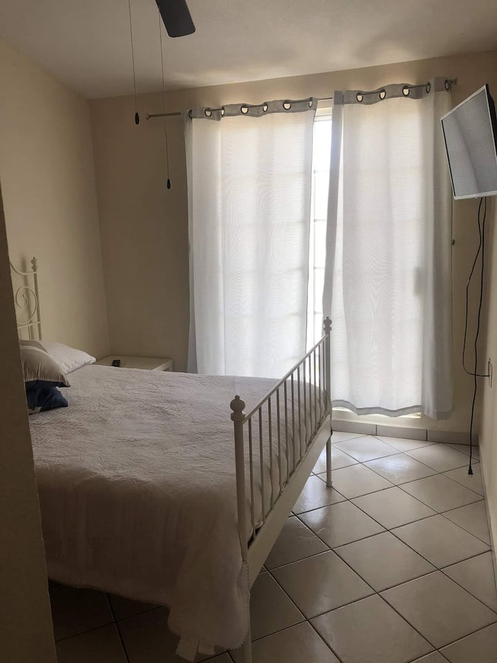 Spavaća soba s bračnim krevetom, TV-om,  balkonom i ormarom.