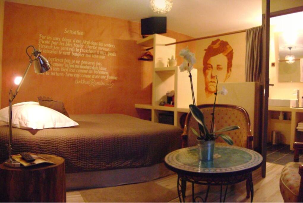 Coin salon, salle de bain ouverte sur la chambre