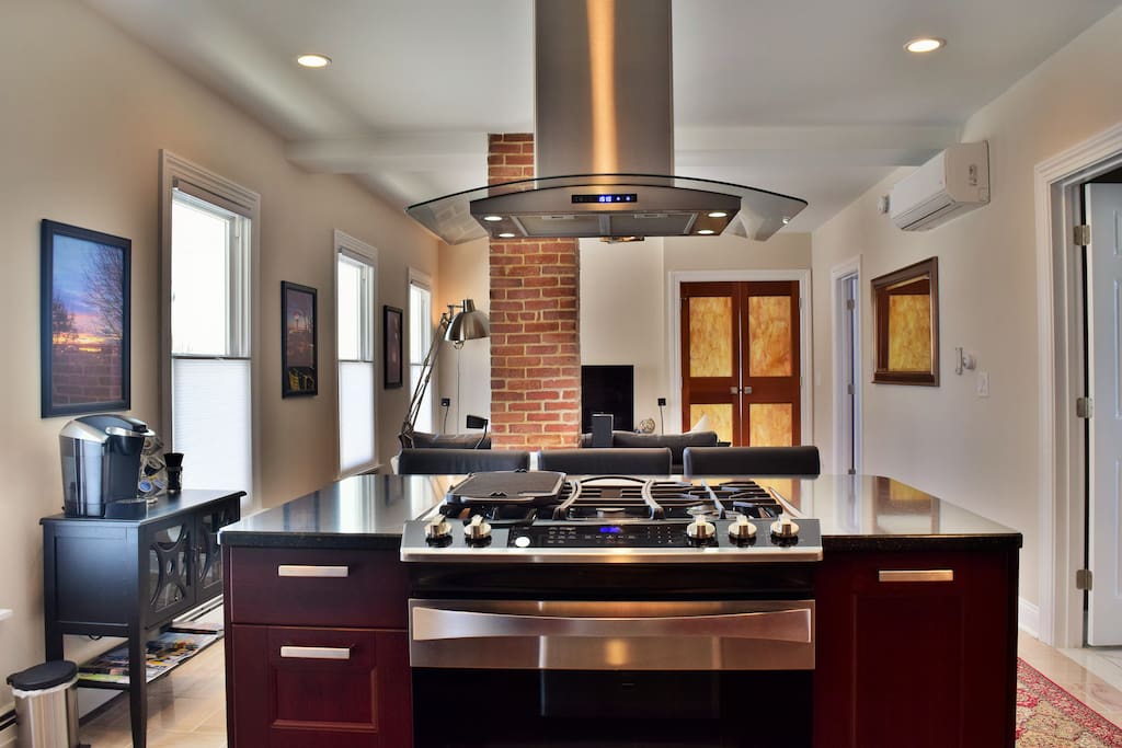 The island with a European style range hood and quartz countertop.