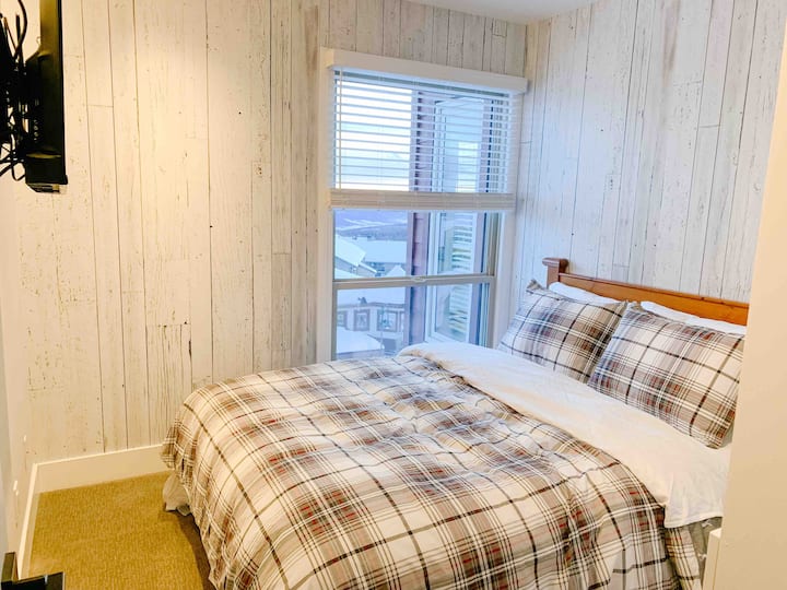 Dormitorio con cama tamaño queen y televisión.