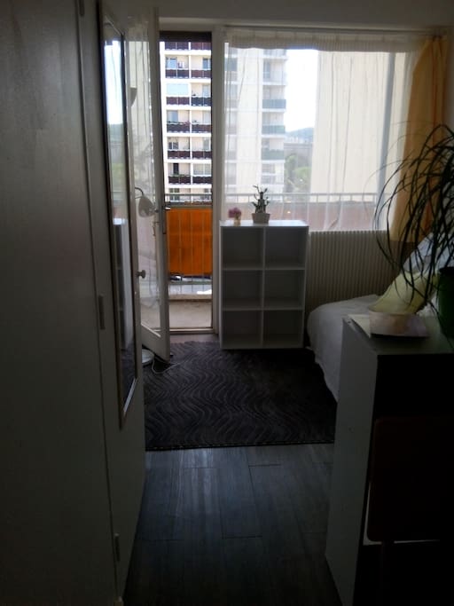 Le salon, vu depuis la porte d'entrée. LA CHAMBRE EST AU FOND A GAUCHE (pas de photo sur le site, mais il y a un lit simple, un grand bureau, la même grande fenêtre et balcon, l'accès à la salle de bain, et 2 placards pour les vêtements)