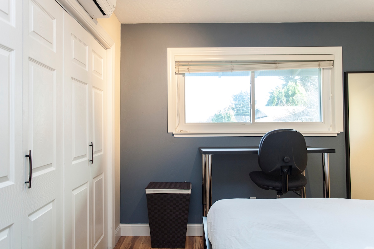 Druhá spálňa s manželskou posteľou Queen, písacím stolom a veľkým oknom.