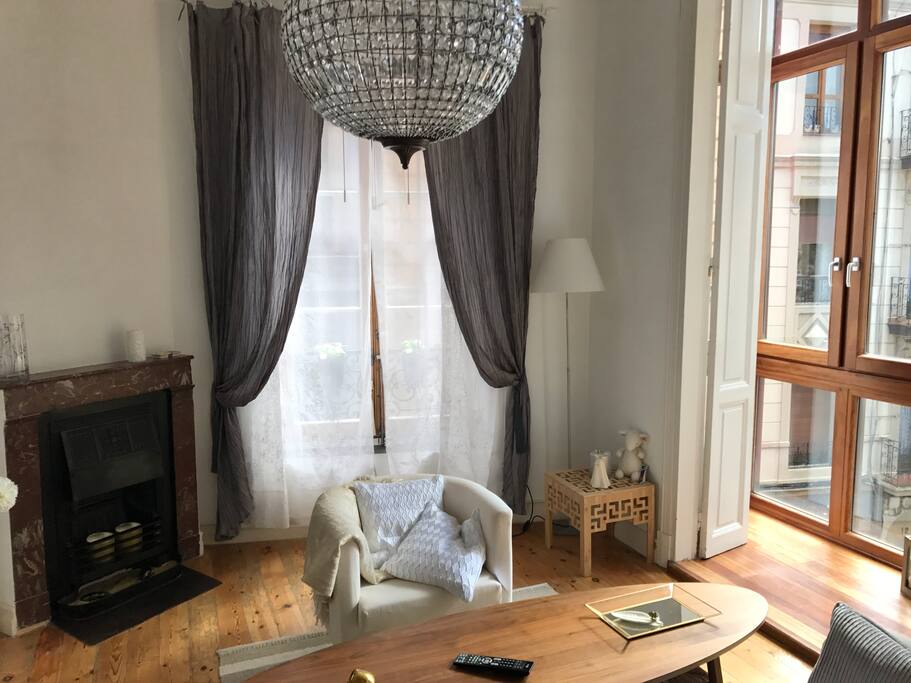 Salon con chimenea forma de trapecio y tres paredes con ventanas.