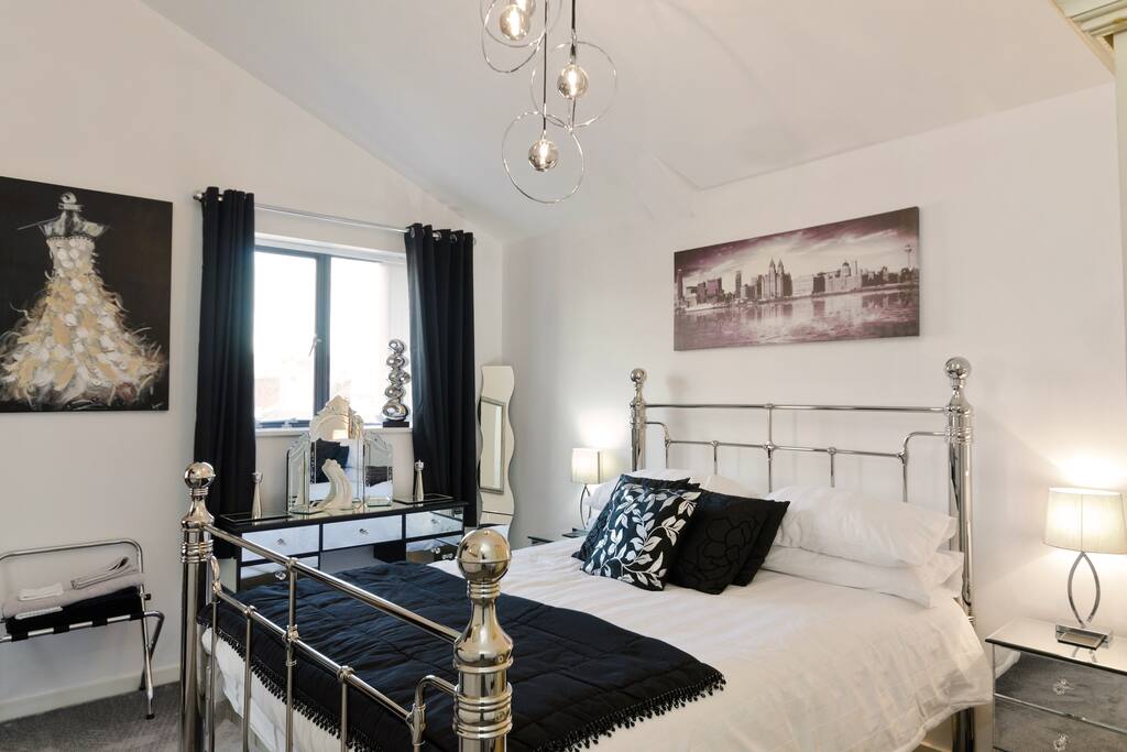 Bedroom with black and white theme, iron bedstead and memory foam mattress and high vaulted ceilings.