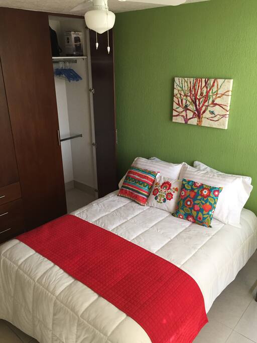 Una cama matrimonial, ventilador de techo y closet disponible con ganchos