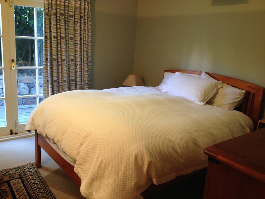 Bedroom 1 - Queen bed. Blackout curtains. Enjoy access to a private garden. Listen for the tui and morepork.