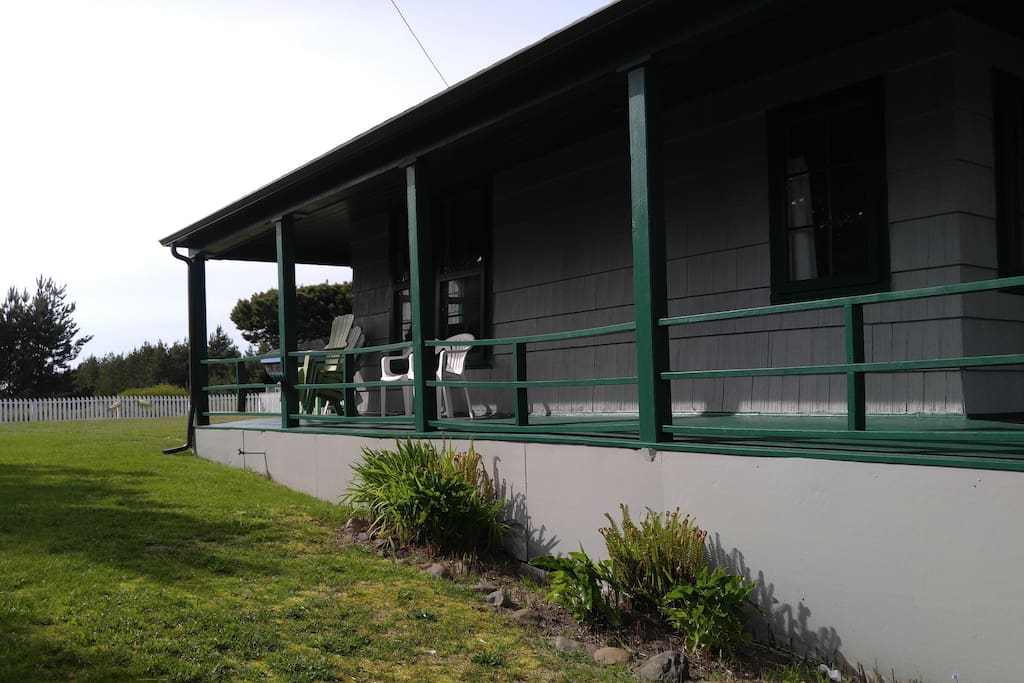 Showing the large picket-fenced garden and wrap-around porches of the cottage.
