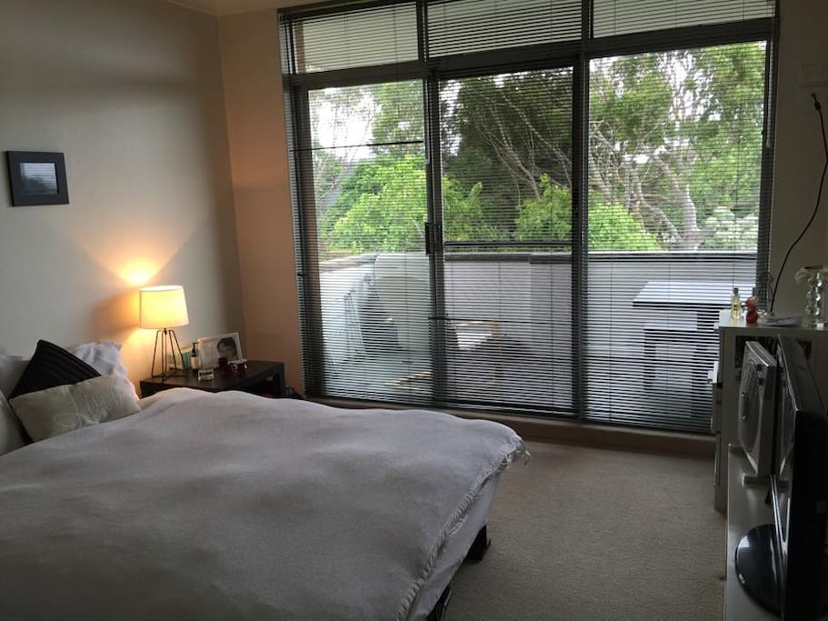 large and light filled master bedroom with balcony access and TV