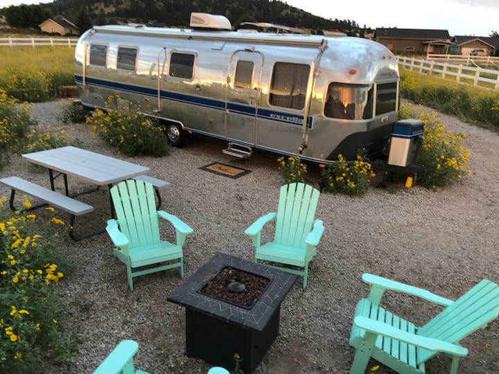 outside view of Airstream with fire pit and chairs