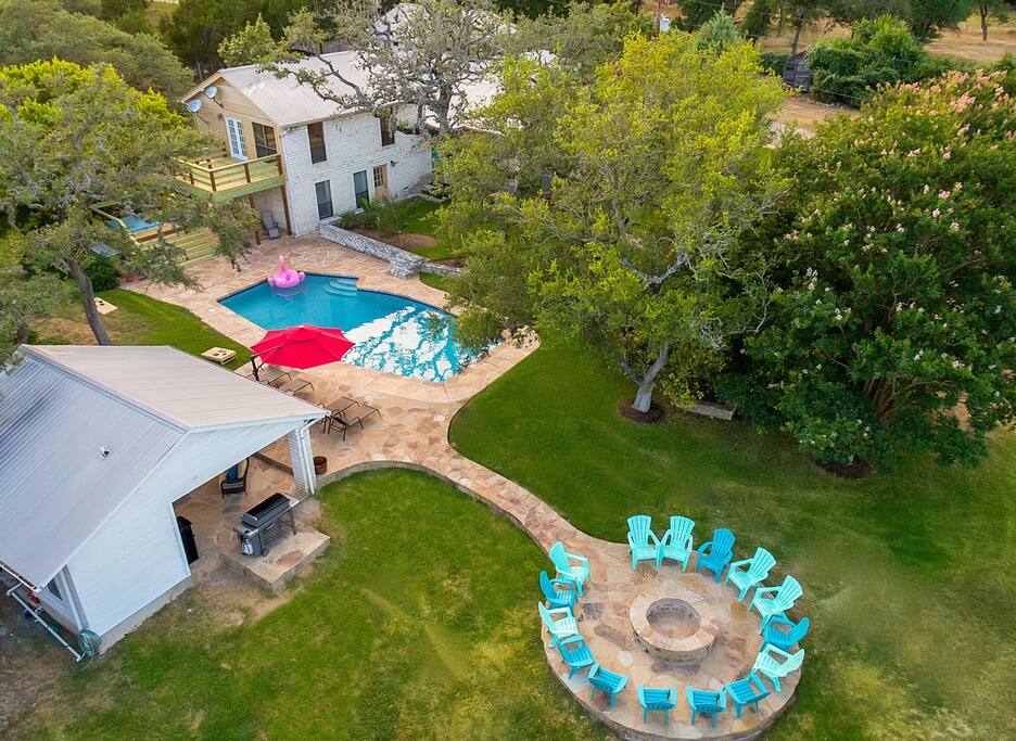 This drone shot provides a great perspective on how much space you have all around the pool for relaxing and enjoying yourselves. The pool house has the biggest grill Weber manufactures (6 burner) which provides ample room for all of your grilling needs, a 65in high definition TV with the complete DirecTV satellite programming, a wet bar, refrigerator/freezer, a blender for mixing drinks and a very large 1/2 bath. You can also see our 10,000 gallon rain water collection tank which helps us conserve the water from our aquifers. We provide firewood for building a fire in the fire pit. Its always fun sitting around telling stories and roasting s'mores.