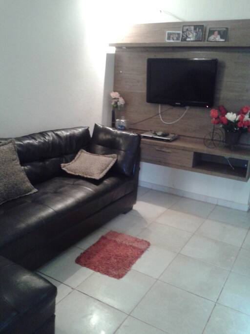 Sala com sofá, almofadas e TV