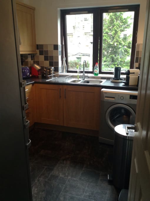 Spacious kitchen with access to fridge, washing machine and other utilities.
