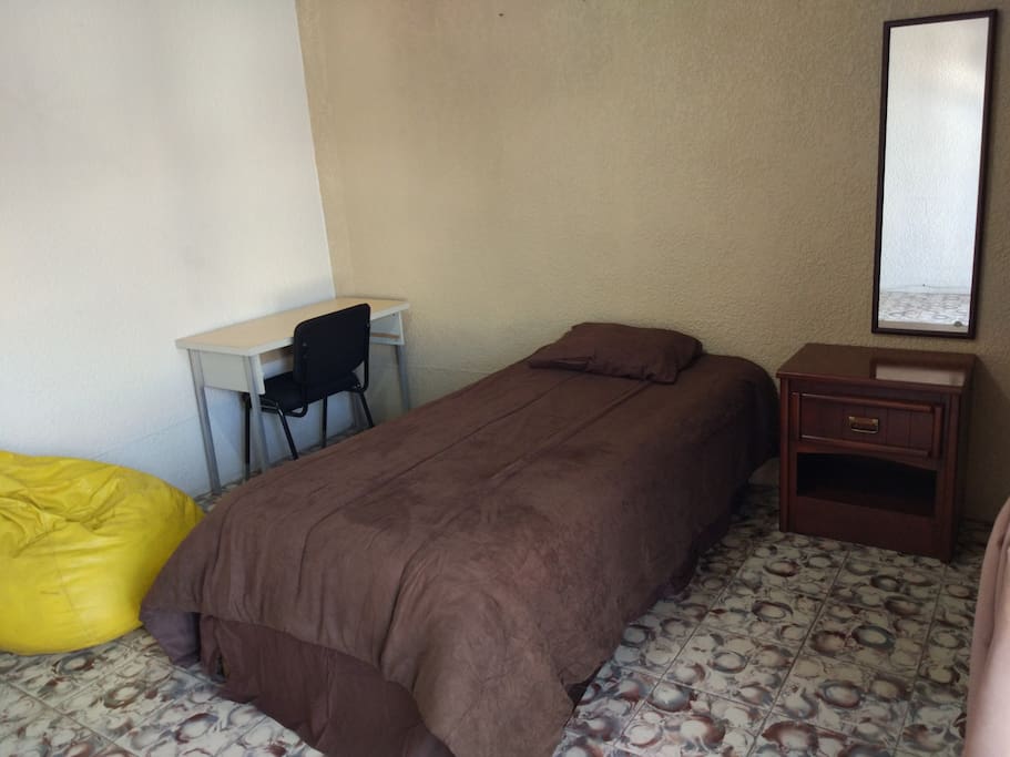 Habitación con cama individual, closet con caja de seguridad, puff de descanso, escritorio y balcon