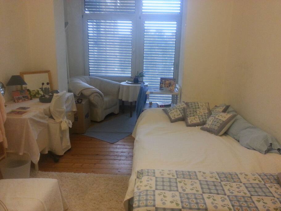 Zwei-Zimmer Aufteilung mit Bett, Sessel und Schreibtisch / Cozy room with bed, wingchair and desk