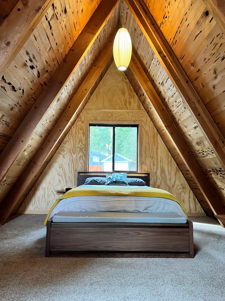 Loft master bedroom with queen bed and bench. 