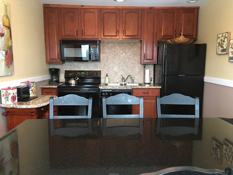 Fully equipped kitchen has granite countertops with a view of mountains & ski jump.