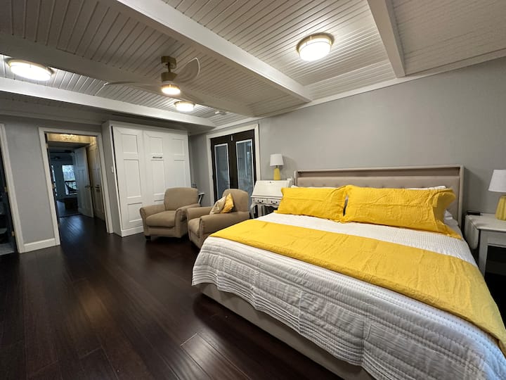 Primary Bedroom w ensuite bath. New in 2024, King bed, Fan & lighting, double Nest swing, 70” TV w Direct TV. Queen Murphy bed. French door access to front porch for sunrise coffee / teas w/out disturbing other guests.  Main level. 