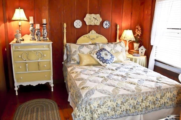 Dormitorio queen en la planta superior con muebles antiguos, pisos de pino y paredes