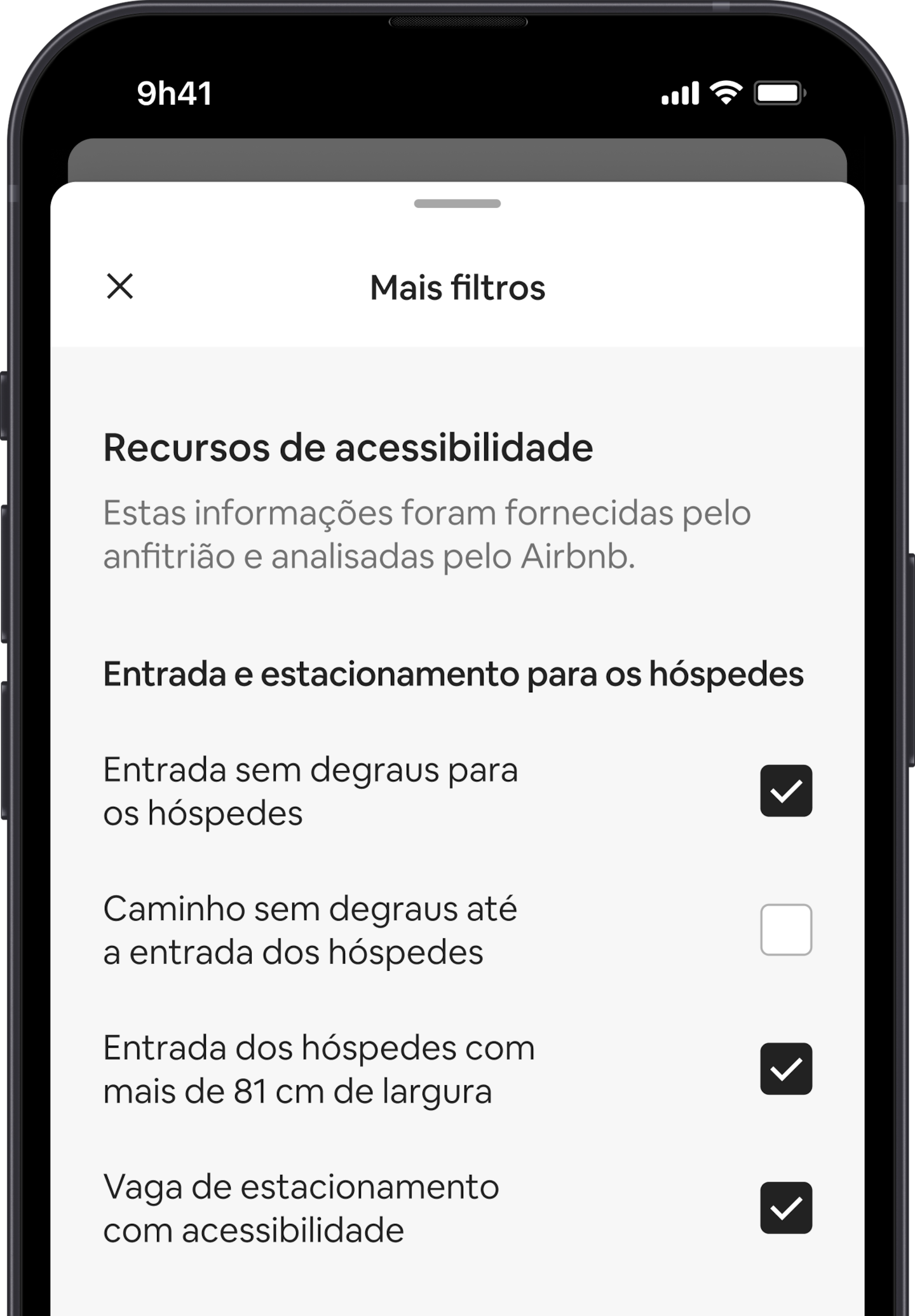 Um telefone celular exibe a sobreposição Mais filtros, uma das muitas opções nos filtros de busca. Há um cabeçalho de seção que diz "Recursos de acessibilidade". Abaixo, os recursos de acessibilidade são agrupados por áreas como "Entrada e estacionamento para os hóspedes". Você pode escolher quantos recursos quiser marcando as caixas de seleção.