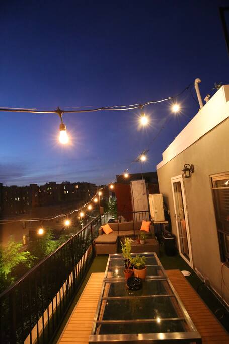 Private patio with couch, table, grill, lights, and wireless speaker system
