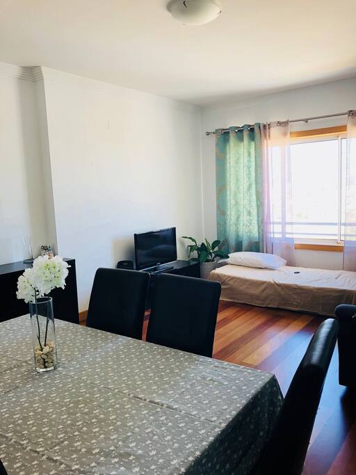 Sala com mesa de jantar, sofá, mais uma cama solteiro e TV