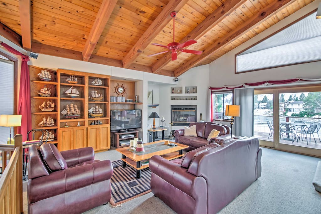 The living room boasts tall, vaulted ceilings and window-framed outdoor views.